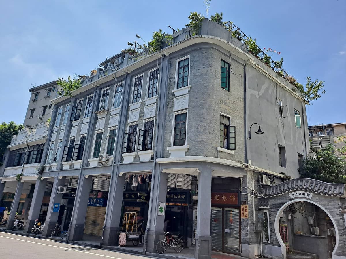 Façade of a restored traditional Lingnan-style building in Guangzhou’s Yongqingfang, with arched entrance, tiled rooftop, and shopfronts beneath residential windows.