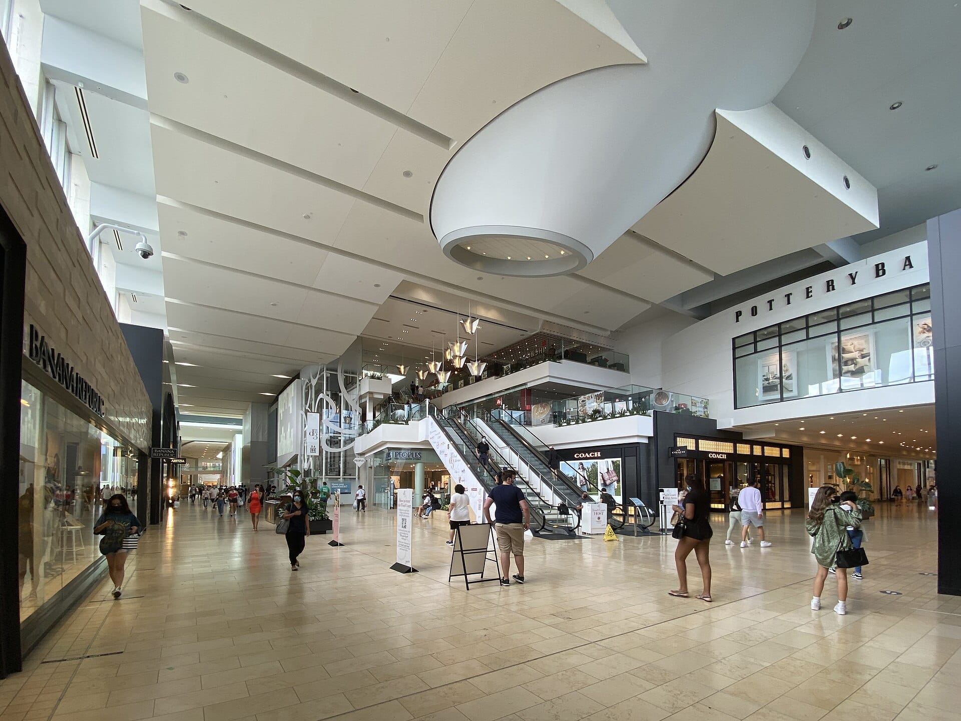 ภาพมุมกว้างภายใน Yorkdale Shopping Centre ที่มีสถาปัตยกรรมสมัยใหม่ เพดานสูง หน้าร้านอย่าง Coach และ Pottery Barn พร้อมนักช้อปที่เดินผ่านบันไดเลื่อน