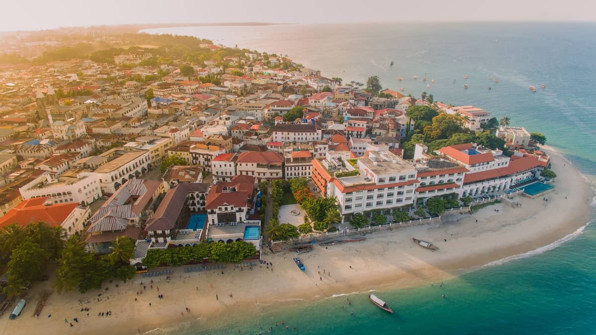 Widok z lotu ptaka na Stone Town na Zanzibarze — historyczne budynki przy nabrzeżu i plaże nad Oceanem Indyjskim o zachodzie słońca.