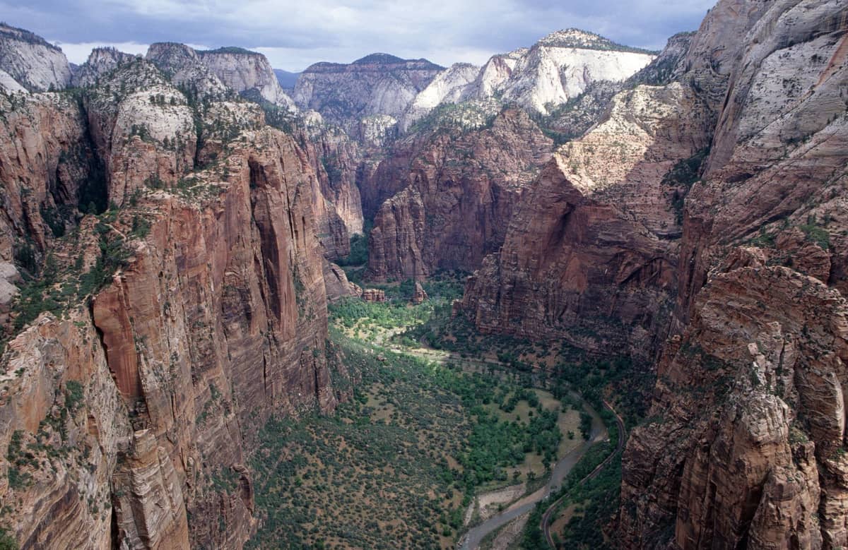 Vista aérea deslumbrante das paredes do cânion do Parque Nacional Zion e do vale verdejante com um rio serpenteante abaixo, mostrando falésias dramáticas e paisagens de tirar o fôlego.