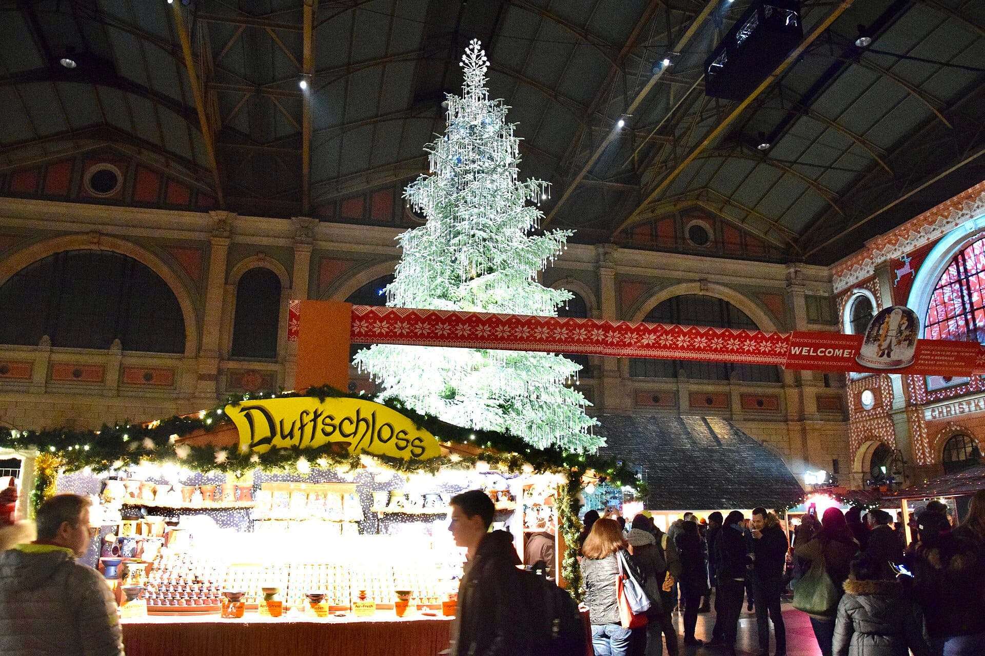 มุมกว้างภายในสถานี Hauptbahnhof Zurich โชว์ตลาดคริสต์มาส Christkindlimarkt และต้นคริสต์มาส Swarovski ขนาดใหญ่ พร้อมร้านค้างานเทศกาลในร่ม