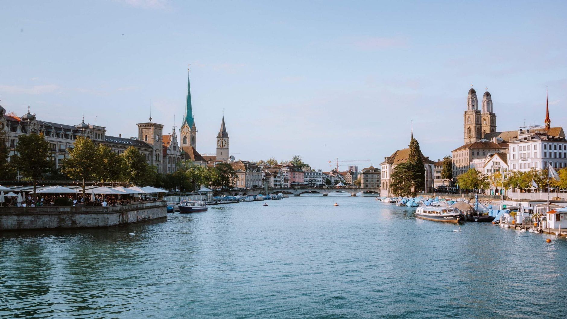 วิวแม่น้ำกว้างของเมืองซูริกพร้อมกับ Grossmünster, Fraumünster และโบสถ์รวมถึงอาคารประวัติศาสตร์อื่นๆ ที่มองเห็นได้ตลอดแนวริมน้ำ