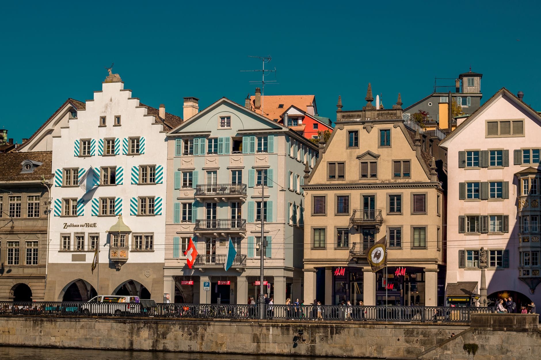 บ้านกิลด์ Zurich หลากสีหลายหลังมีสถาปัตยกรรมโดดเด่นเรียงติดริม Limmatquai มองเห็นเด่นชัดในแสงแดดยามสายเลียบแม่น้ำ