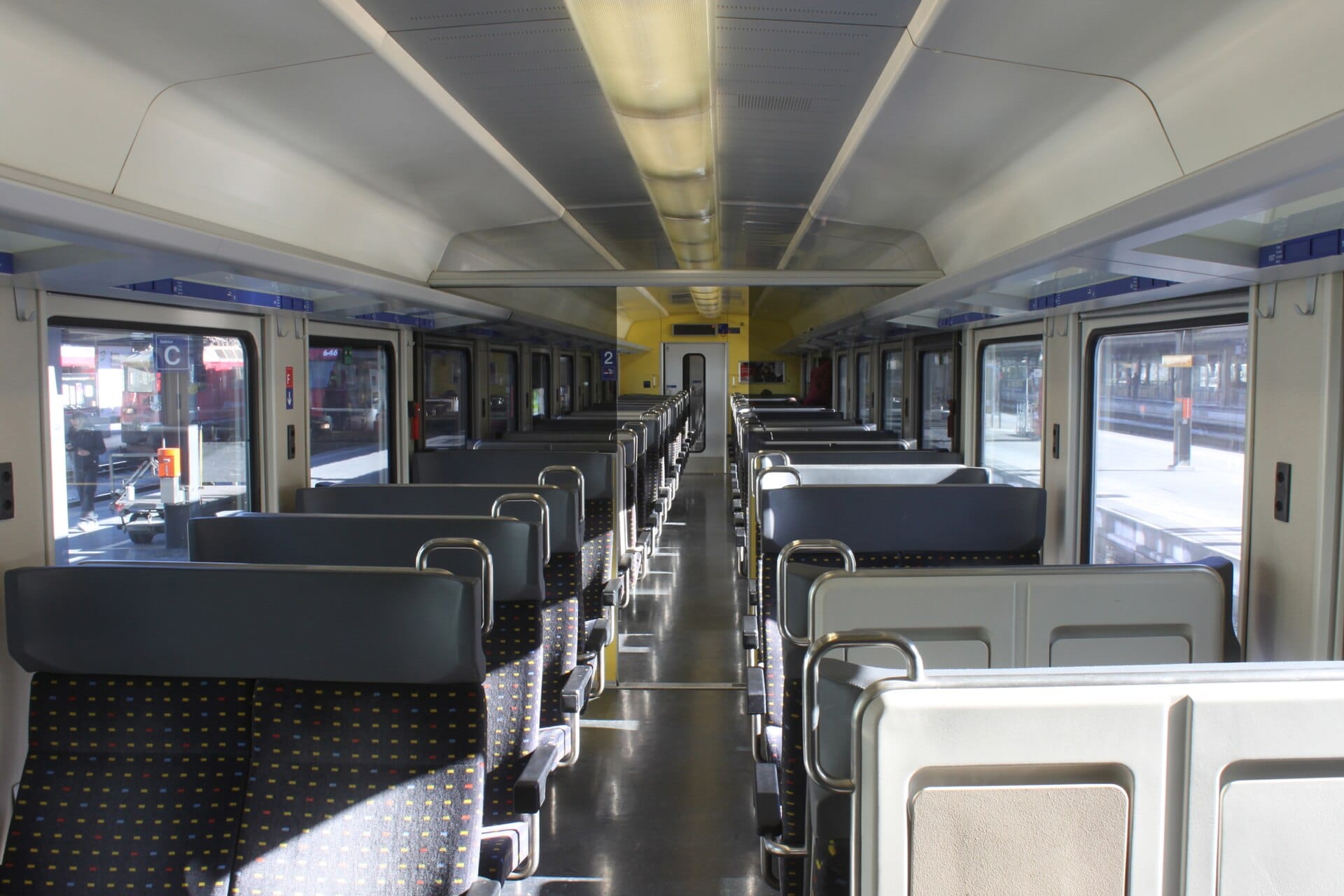ภายในตู้โดยสารรถไฟอินเตอร์รีเจียนนัล SBB ของสวิตเซอร์แลนด์ที่สว่างและสะอาด พร้อมที่นั่งทันสมัย ทางเดินกว้าง และหน้าต่างบานใหญ่บนชานชาลาสถานี