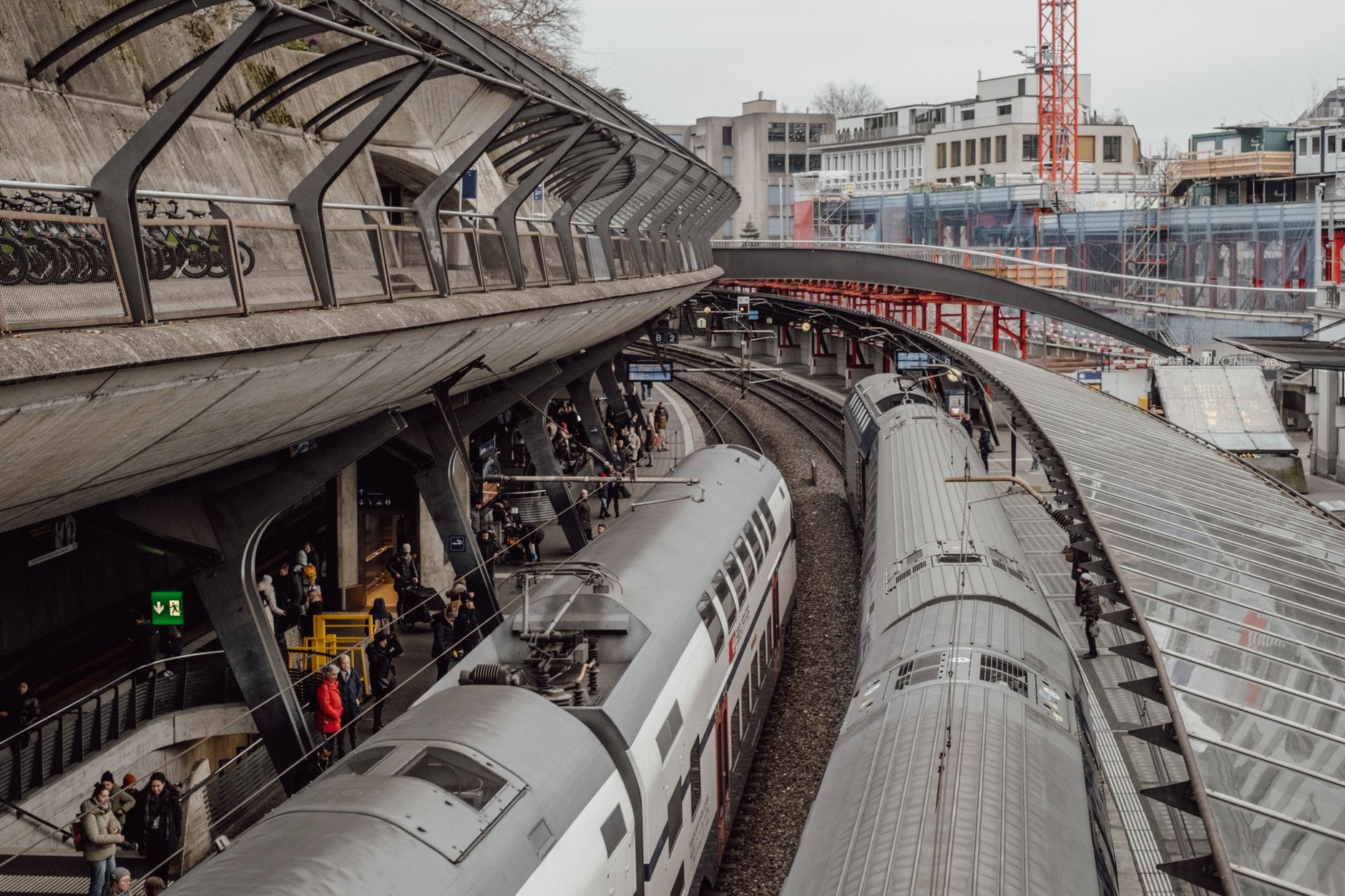 รถไฟสวิสสมัยใหม่ที่สถานีหลัก Zurich พร้อมผู้โดยสารบนชานชาลาและหลังคากระจกที่โดดเด่นเหนือรางรถไฟ